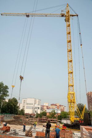 Tyumen, Russia - July 31, 2013: JSC Mostostroy-11. Construction of 18-storeyed brick residental house at the intersection of streets of Nemtsov and Tsiolkovsky. Crane on residential building construction in summer dayのeditorial素材