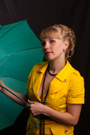 Portrait of attractive caucasian woman blond with green umbrella isolated on black studio shotの写真素材