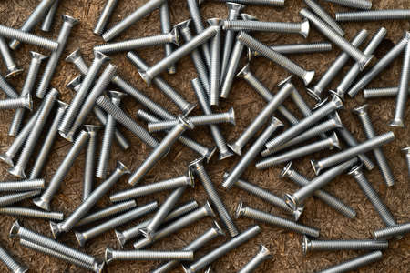 Stainless steel screws on wooden background