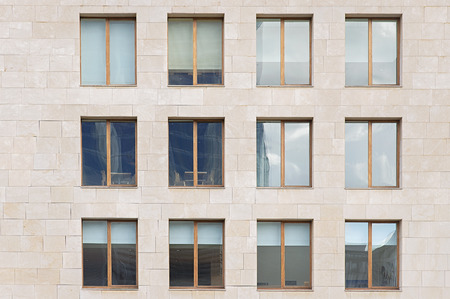 Beige stone wall with many windows close up