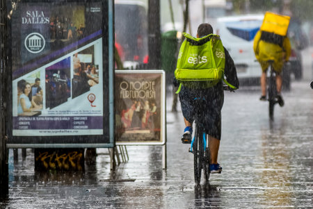 Bucharest, Romania - August 01, 2019: An Uber Eats food delivery courier delivers food, in rainy weather, in downtown Bucharest, Romania.のeditorial素材