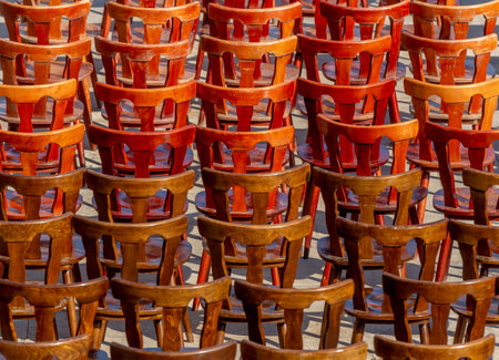 Bucharest, Romania - July 19, 2019: Many old designed wooden chairs painted with reddish stain are laid on an esplanade after a public event in Bucharest.のeditorial素材