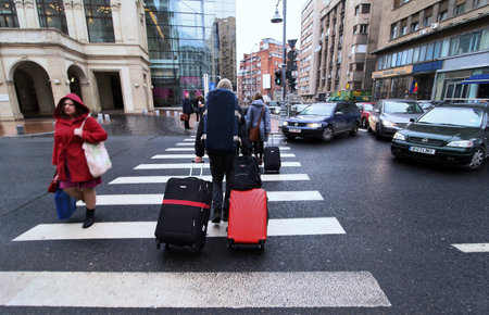Bucharest, Romania - February 22, 2019: Tourists carrying suitcases are crossing the Victoriei Avenue, in downtown Bucharest, Romania. This image is for editorial use only.のeditorial素材