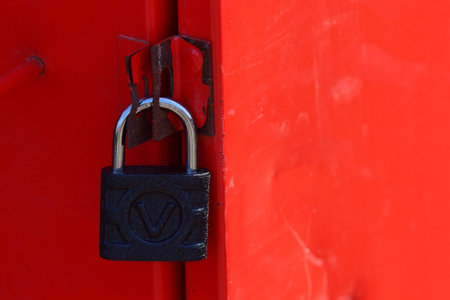 Bucharest, Romania - March 31, 2019: A black padlock closes a red rusty iron door.のeditorial素材