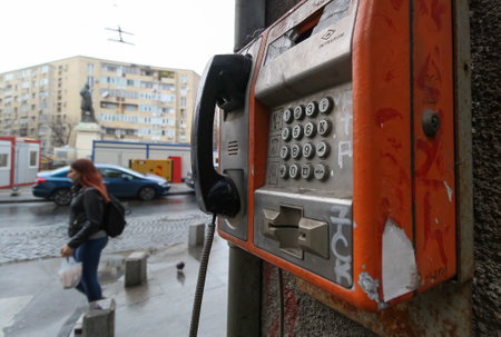 Bucharest, Romania - November 15, 2018: An out of use old public telephone with buttons in an advanced state of degradation is mounted on wall in downtown of Bucharest.のeditorial素材