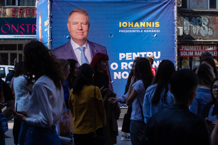Bucharest, Romania - September 30, 2019: Young people pass by a billboard of the electoral campaign of Klaus Iohannis, the president of Romania, who is running for the second presidential term.のeditorial素材
