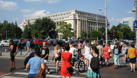 Bucharest, Romania - July 14, 2021: People cross the street near the Victoria Palace which houses the Romanian Government headquarters, in Bucharest.のeditorial素材