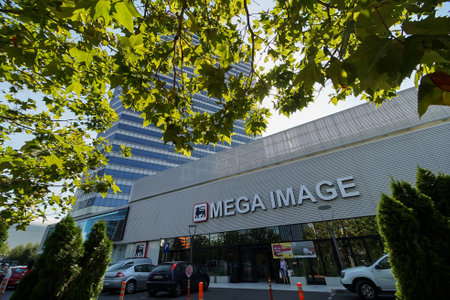 Bucharest, Romania - August 16, 2021: A patch of light falls on the front of the Mega Image Concept Store from the Globalworth Tower ground floor in Bucharest This image is for editorial use only.のeditorial素材