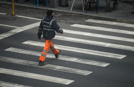 Bucharest, Romania - December 16, 2021: A construction worker crosses the street on the crosswalk. This image is for editorial use only.のeditorial素材