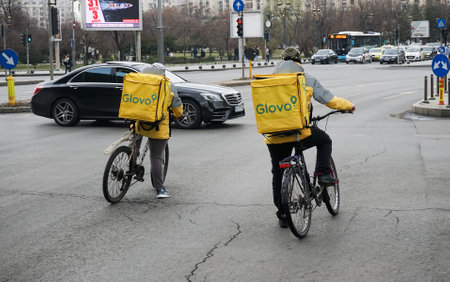 Bucharest, Romania - March 07, 2022: Two Glovo food delivery couriers delivers food in Bucharest, Romania.のeditorial素材