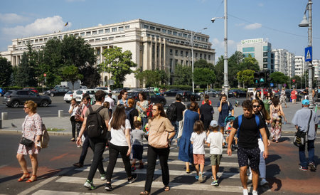 Bucharest, Romania - July 14, 2021: People cross the street near the Victoria Palace which houses the Romanian Government headquarters, in Bucharest.のeditorial素材