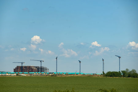 Tunari, Romania - Mai 24, 2023: Construction cranes can be seen at the housing blocks under construction on the territory of the commune of Tunari, north of Bucharest. This image is for editorial use only.のeditorial素材
