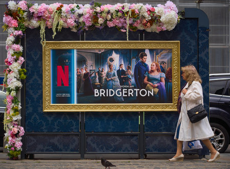 Bucharest, Romania. 15th May, 2024: People pass by an advertising of Netflix Bridgerton TV Series is displayed on a flower-decorated bus station in the center of Bucharestのeditorial素材