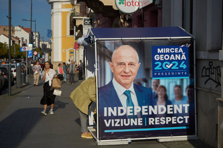 Cluj-Napoca, Romania. 20th Sep, 2024: People walk past an electoral tent banner of the independent candidate for the presidency of Romania, Mircea Geoana, the former NATO Deputy Secretary General.のeditorial素材