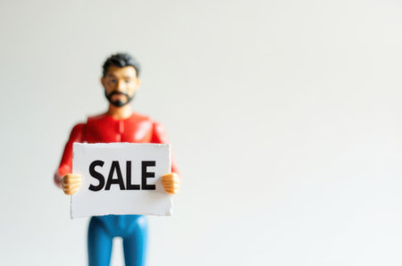 Miniature people : A man holding sale sign on white background.の素材