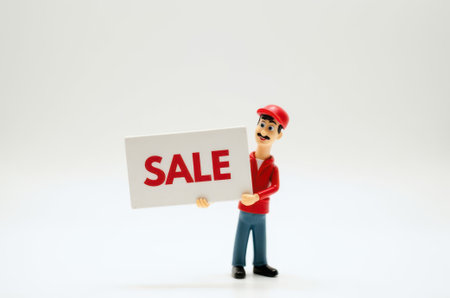 toy man holding a sign with the text Sale on a white backgroundの素材