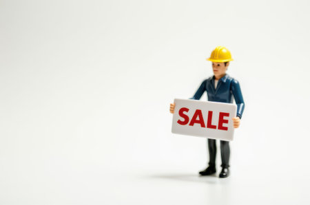Miniature people engineer holding sale sign on white background with copy space.の素材