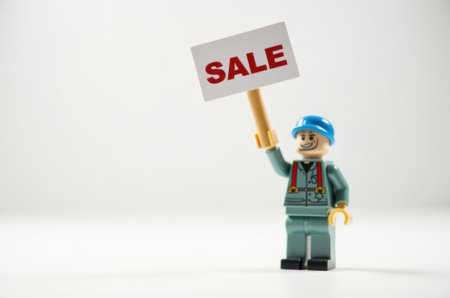 toy man holding a sign with the text Sale on a white backgroundの素材