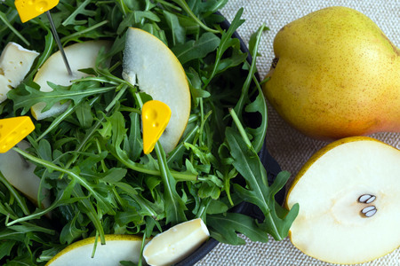 Two big sweet pears near the black plate. Easy tasty summer salad with pear, arugula, brie cheese, pine nuts, honey sauce. The recipe for proper nutrition. Healthy lifestyle. Durability.の写真素材