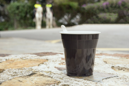 Strong coffee in a brown plastic cup on a stone bench. Coffee break while traveling.