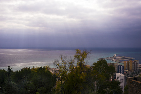 View of the Mediterranean Sea in the Spanish city of Malaga. Bright sun rays make their way through the clouds. Amazing morning.の写真素材