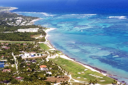 Beautiful top view: turquoise Caribbean Sea, sandy beach, palm grove, hotels on a bright sunny day. Top view from the cockpit of a helicopter.のeditorial素材