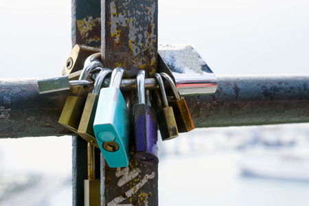 Multicolored love locks, locked on a rusty pipe. Symbol of love and loyalty.の写真素材