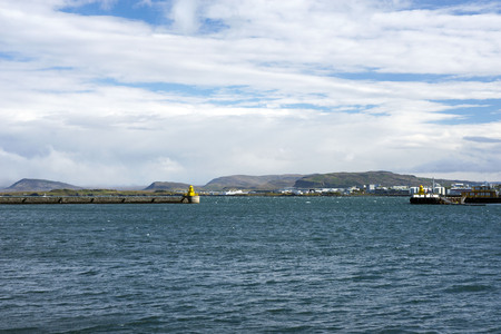 View of the beautiful seascape, Mount Esja, the sea, the port and the yellow lighthouse in the distance in Reykjavik, Iceland.の写真素材
