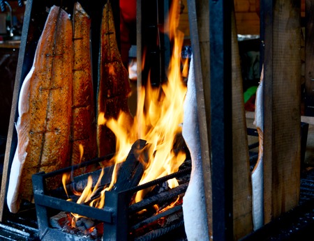 Fresh smoked salmon, mounted on a board and cooked over an open fire and charcoal at a Christmas...