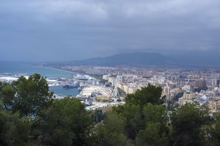 Malaga, Spain, February 2019. Panorama of the Spanish city of Malaga. Buildings, port, bay, ships and mountains against a cloudy sky. Dramatic sky over the city. Beautiful view.のeditorial素材
