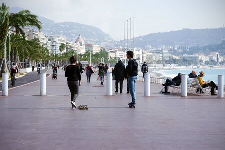 Nice, France, March 2019. Two young people: a boy and a girl ride a skateboard along the promenade. Cote d'Azur. Promenade des Anglaisのeditorial素材
