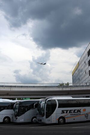 Germany, Frankfurt am Main, June 2019. Airplane in the sky among the clouds. Lufthansa's large white passenger liner takes off before a thunderstorm.  In the foreground is the bus stop.のeditorial素材