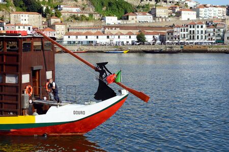 Porto, Portugal, June 2019. Embankment of the Douro River. Silhouette of a woman and the flag of Portugal on the bow of a wooden boat. Pleasure boat on the Douro River, Porto.のeditorial素材