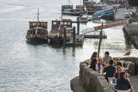 Porto, Portugal, June 2019. Embankment of the Douro River at sunset time. Tourists and residents of Porto stroll along the embankment, dine in a restaurant, ride a boat on the river. Journey.のeditorial素材
