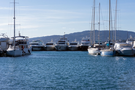 White expensive yachts on a background of mountains on a sunny day. Yacht parking in Cannes, France. Mediterranean Sea.のeditorial素材