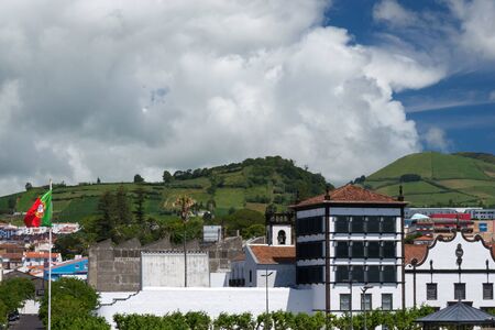 Beautiful view of the mountains, roofs of houses and streets of the city of Ponta Delgada, Portugal. Gray rain clouds over the city. Azores, the island of San Miguel.の写真素材