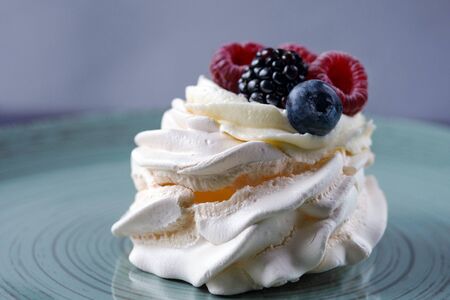 Delicious crispy meringue cake with fresh berries. Raspberries and blueberries in the famous dessert of Anna Pavlova. Popular traditional dessert of New Zealand and Australia.の写真素材