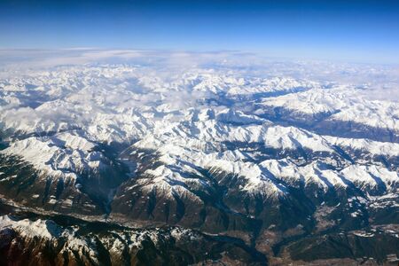 Winter landscape. Beautiful Alps mountains with peaks covered in snow. Photo from the porthole of an airplane.の写真素材