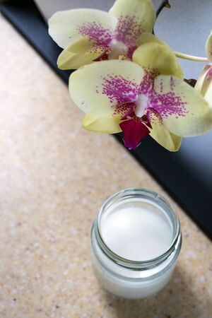 Delicate orchid flowers on a background of tejsklany jars with natural homemade organic yogurt.の写真素材