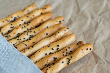 Traditional italian thin crispy grissini sticks with black sesame seeds and cheese linen napkin....