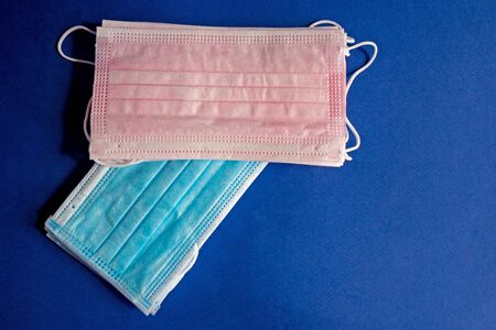Blue and pink medical disposable protective masks on a blue background. Protection concept.