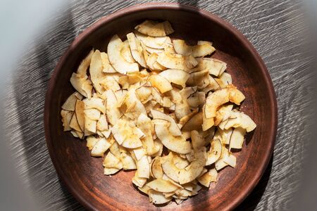 Delicious crispy coconut chips with salted caramel in a brown ceramic plate. Natural product made...