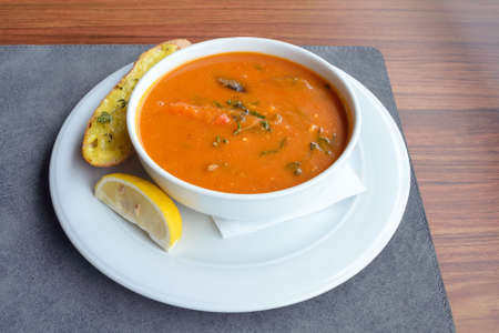 Delicious fish soup Bouillabaisse in a white plate with toasted and rosemary. A dish of traditional...