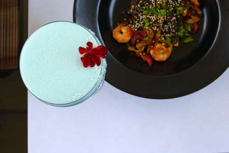 Red flowers on a Blue Daikiri cocktail in a glass goblet on a white background. Alcoholic drink. View from above. Romantic dinner.の写真素材