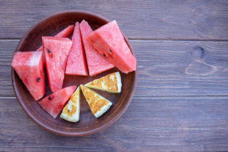 Delicious summer snack. Grilled salty Levantine halloumi cheese and slices of sweet watermelon on a wooden background. Traditional Cypriot cuisine.の写真素材