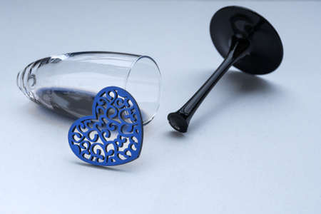 Small red heart and broken wine glass. Broken love, depression and hopelessness concept. Tinted classic blueの写真素材