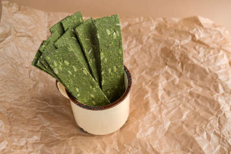 Vegetarian chips with seaweed. Crispy chips with spirulina, flax seeds, ginger and wasabi on craft paper. Marine multi-snacks. Superfood. The concept of proper nutrition.の写真素材