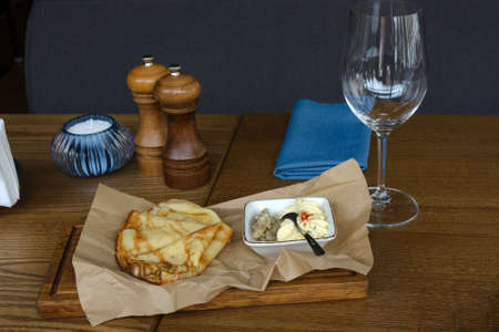 Delicious fried pancakes on craft paper and Israeli traditional forshmak appetizer in a restaurant. East Slavic traditional Maslenitsa festival. Delicious lunch at the restaurant.の写真素材