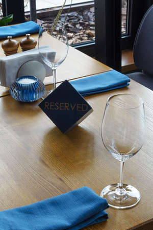 Wooden blue cube with "Reserved" written on the serving table. Reserved table in the restaurant.の写真素材