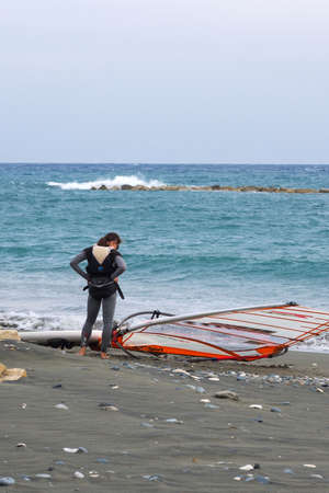 Cyprus, Limassol, February 2020. A girl in a black suit is getting ready to go windsurfing. Water...